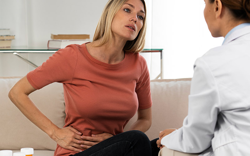 mulher loira consulta médica sobre cólicas e dores abdominais