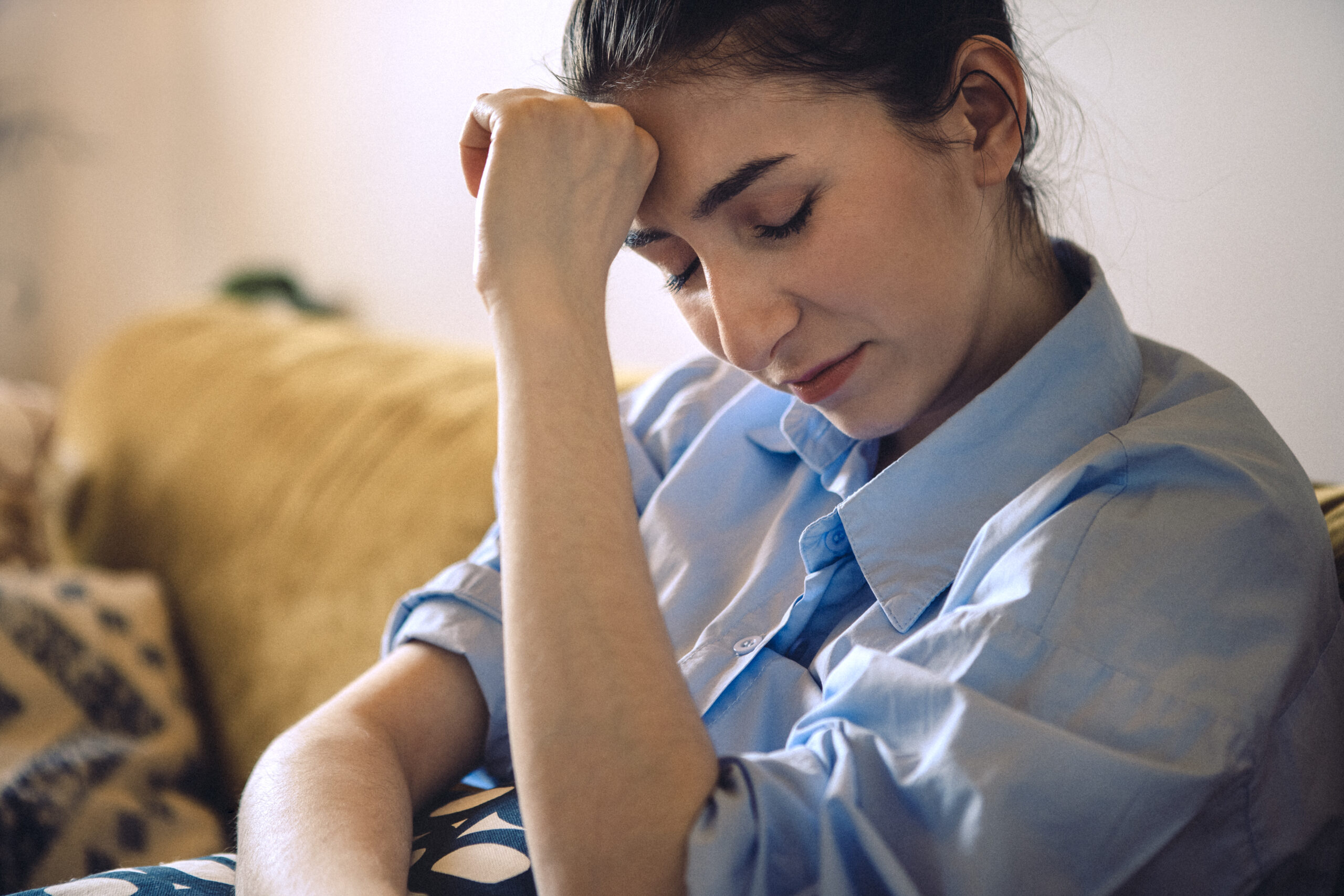 Mulher jovem com expressão de apreensão sentada em consultório médico, representando o impacto emocional e físico do vaginismo na vida sexual e reprodutiva.